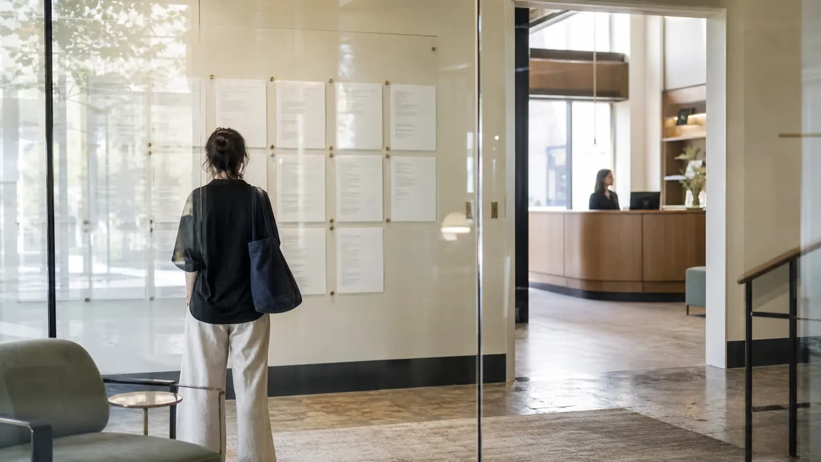Visitor reading public privacy documents displayed on a glass wall in an open office lobby